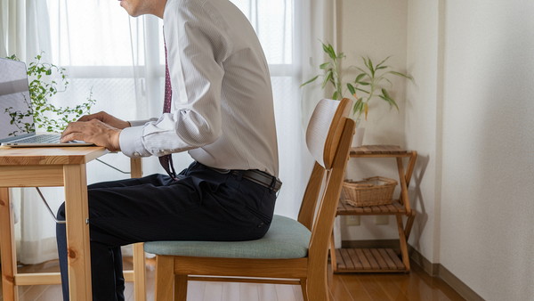 部屋でデスクワークしている男性の姿勢